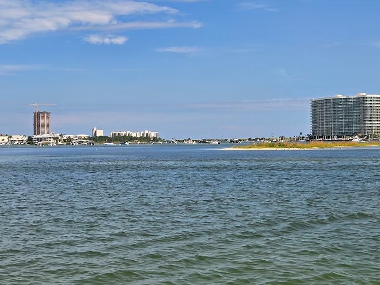 Coastal view with water, buildings, and blue sky.