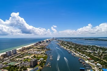 Aerial view of coastal town with buildings, beach, and waterway.