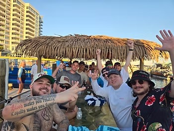 Group of men smiling and raising arms on a boat with a thatched roof.